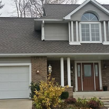 Exterior front facade of a two story home. The roof is newly installed by Guarantee Roofing and Fence in Terre Haute Indiana. The front porch has white columns and a red front door.